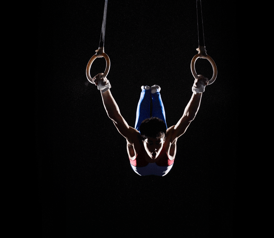 Male gymnast on rings on a black background