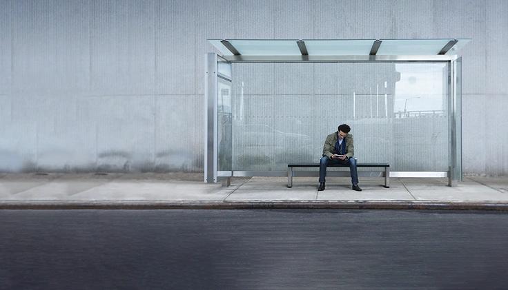 Guy sitting at a bus stop, alone