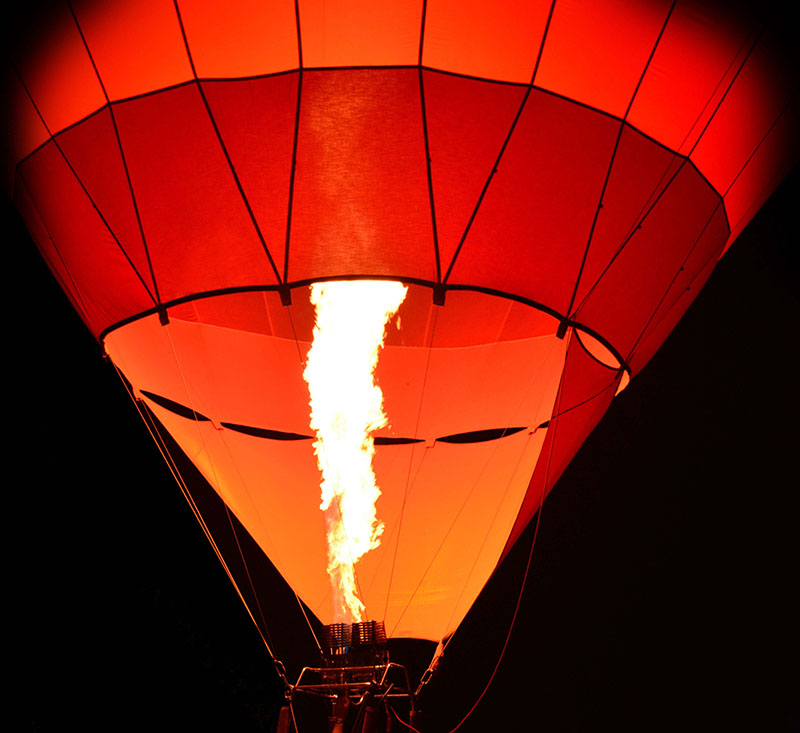 Orange hot air balloon with large fire stream shooting up