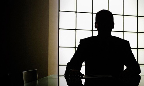 A man sitting in silhouette at a table