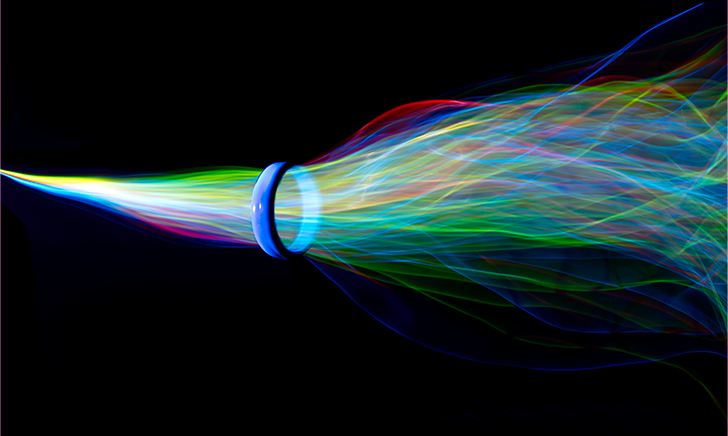 Colorful waves of light energy being funneled through blue hoop on black background.