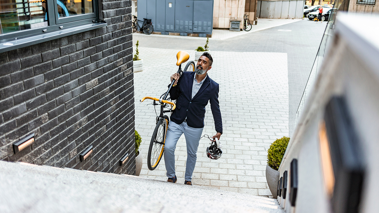 A business executive carries his bike up the stairs to his office building