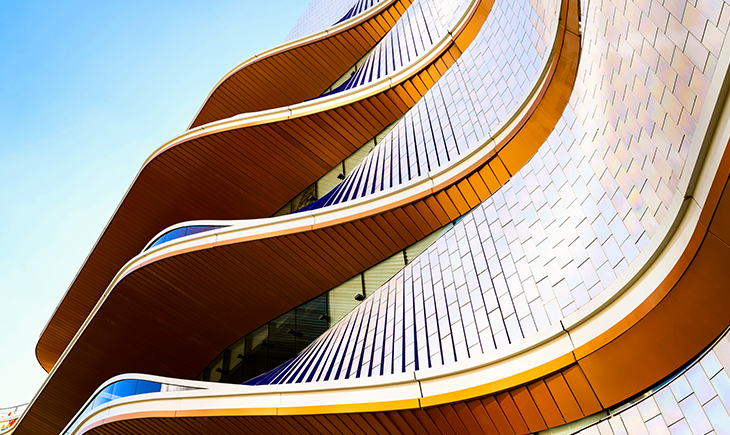 Curved building with rows of windows against a blue sky.