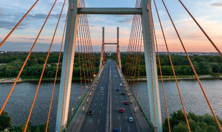 Suspension bridge over river at sunset