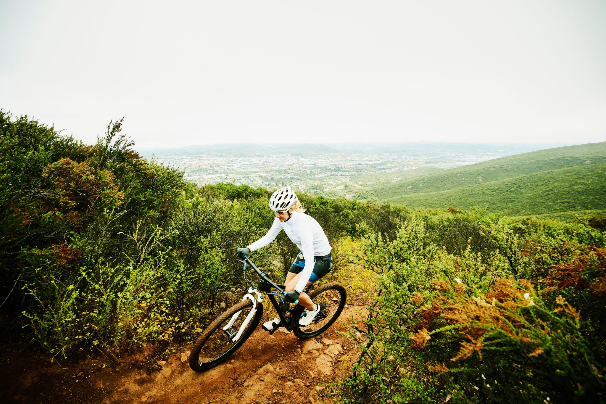 Mature woman climbing up trail during early morning mountain bike ride