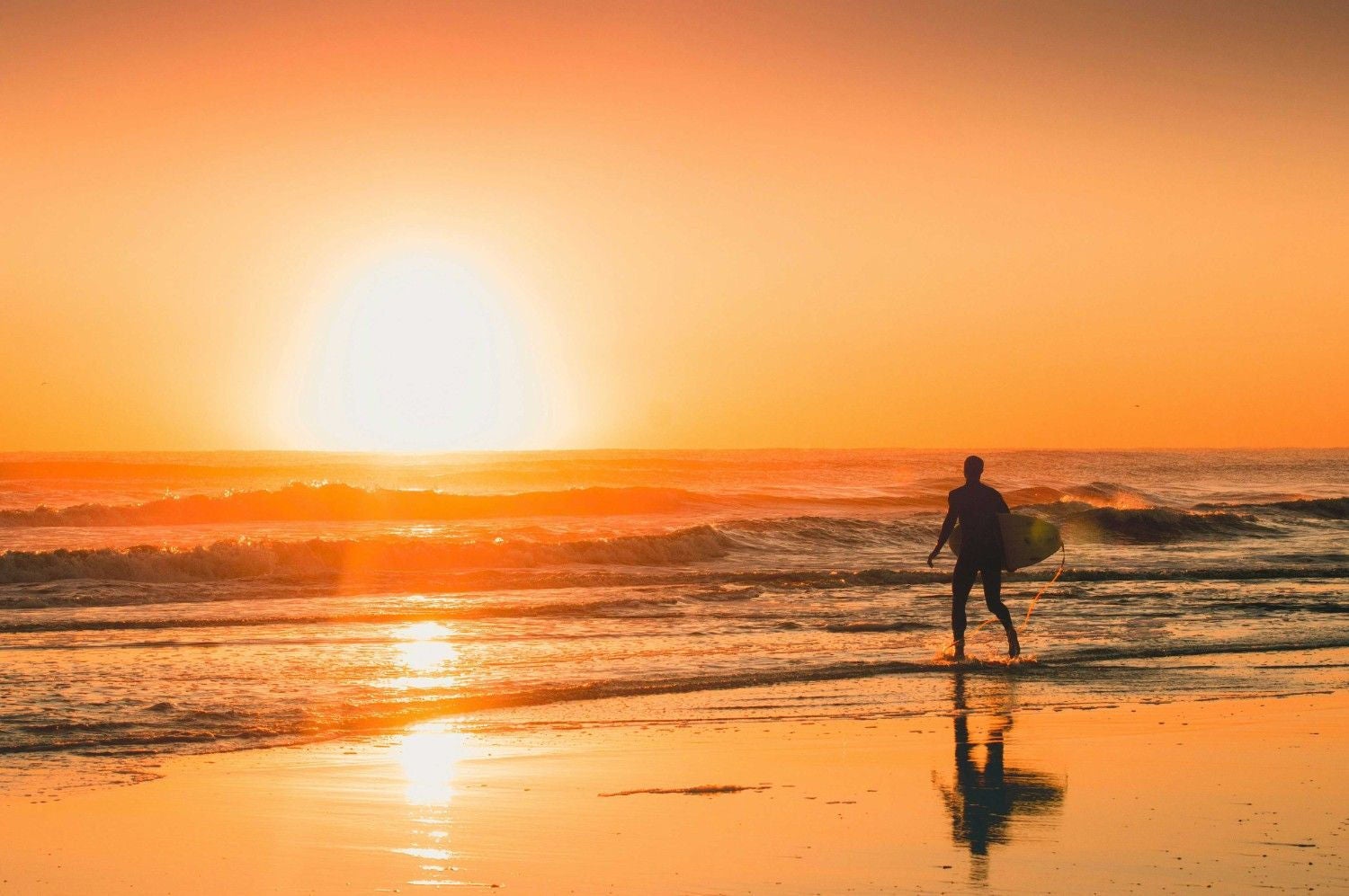 A man holding his surfing board walking towards the sea