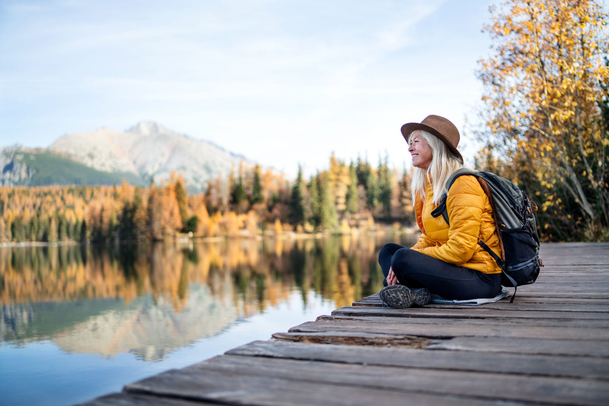 A senior woman sitting by the lake.