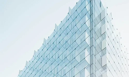Glass-paneled modern building corner against a pale sky.