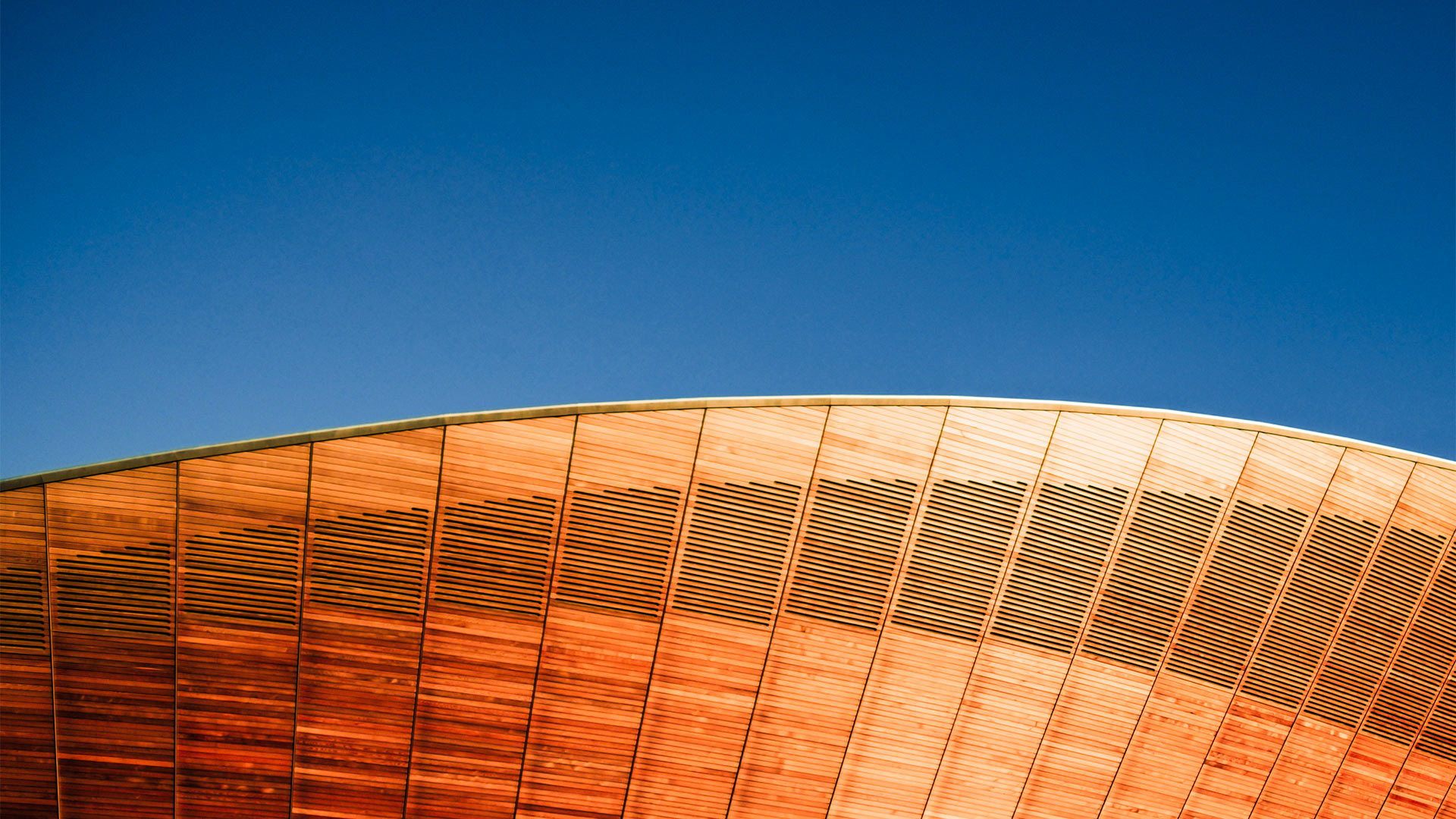 Curved wooden building facade against a blue sky