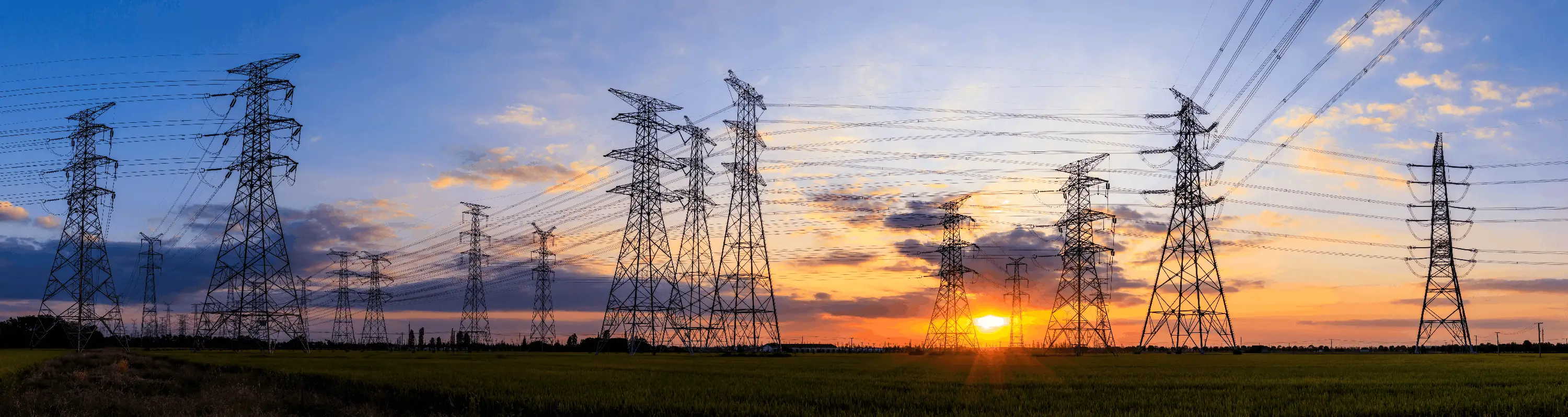 High Voltage Power Lines at Sunset Over Fields