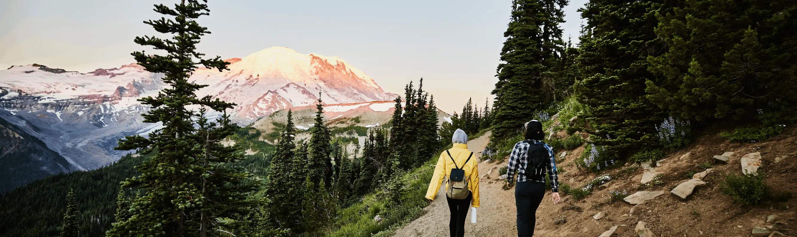 Two hikers walking mountain trail at sunrise