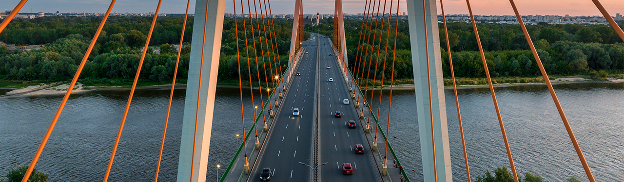 Cable-stayed bridge over a river at sunset with light traffic