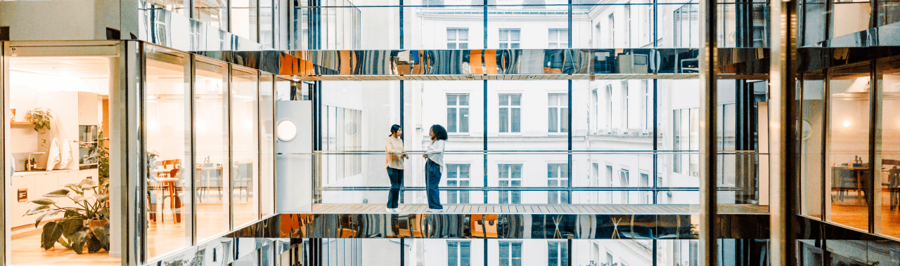 Coworkers talking in modern glass office atrium